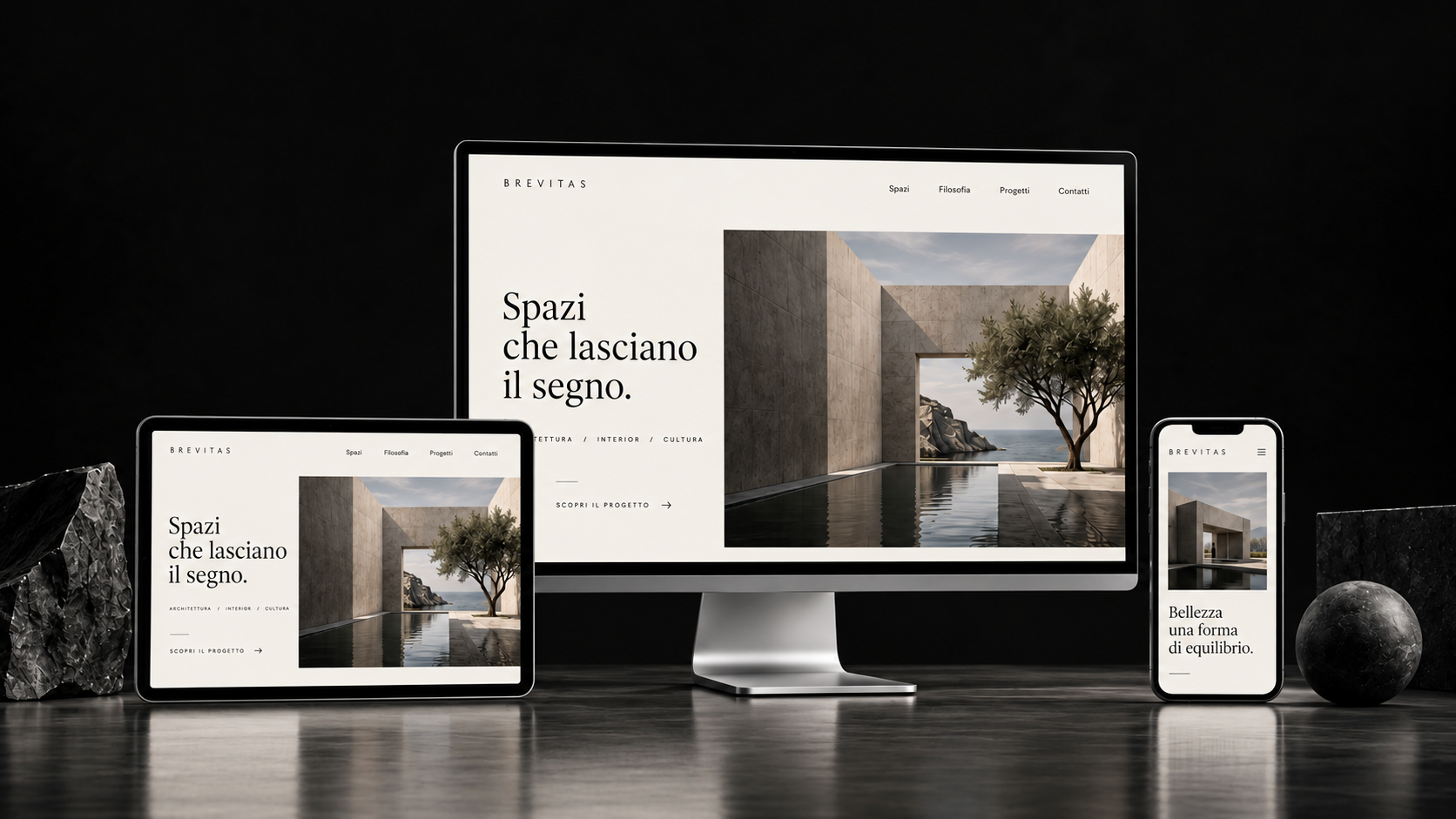 Concept di sito BREVITAS su monitor, tablet e smartphone, ambientati tra pietra scura e riflessi soffusi